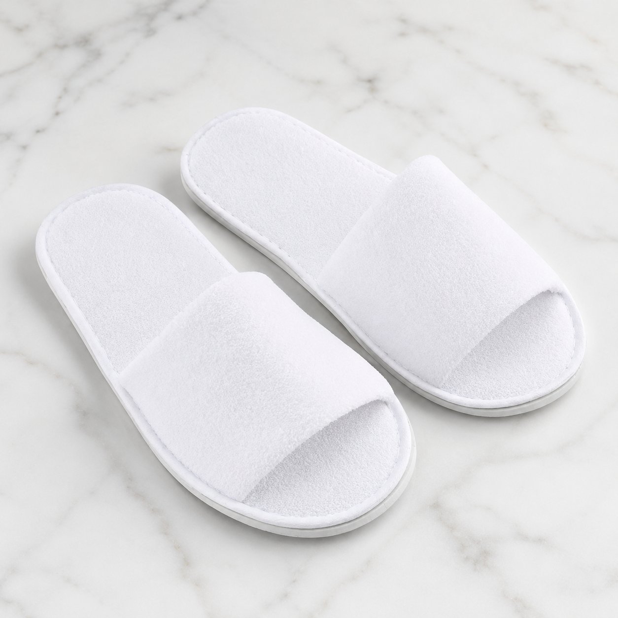 White 4mm open toe disposable spa slippers on a light marble background for salon, spa, hotel, pedicure, and treatment room use.